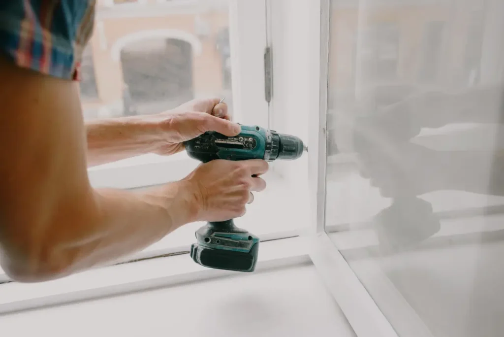 En person använder en borrmaskin på en fönsterkarm