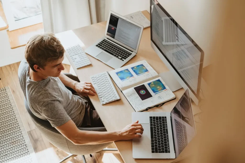 Kille jobbar med sin dator och tre skärmar och han behöver IT support eller teknikhjälp i hemmet