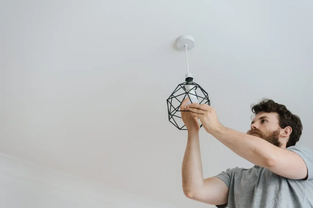 Man fixar lampa som sitter i taket